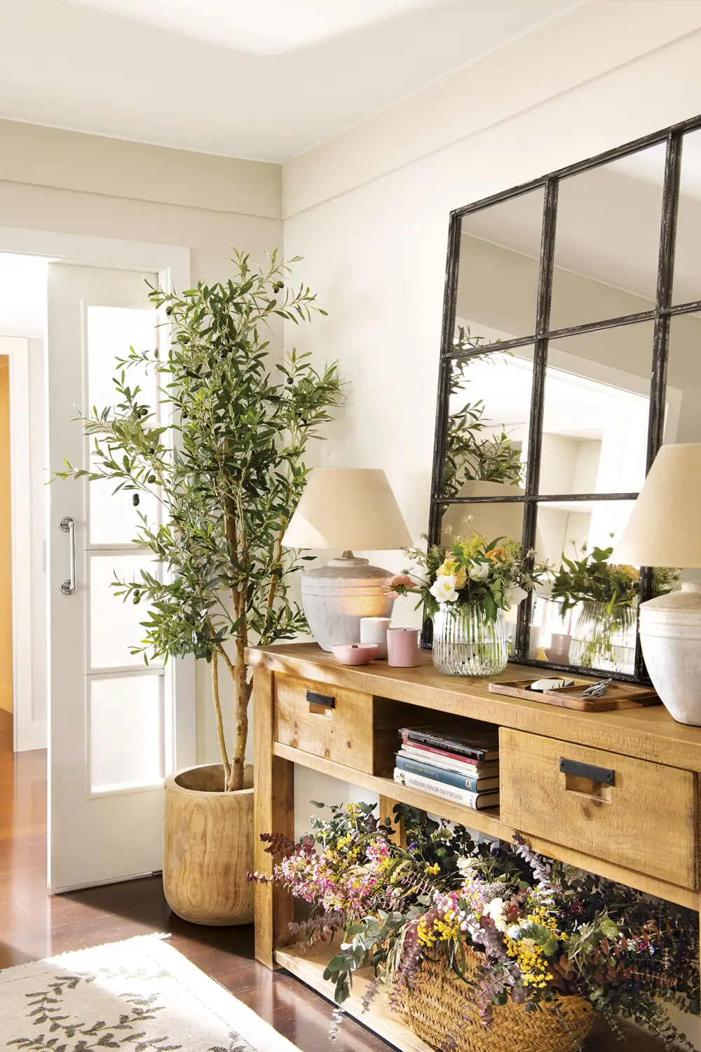 recibidor con mueble de madera rústica con espejo, olivo y flores secas, lámparas de mesa y jarrón de cristal